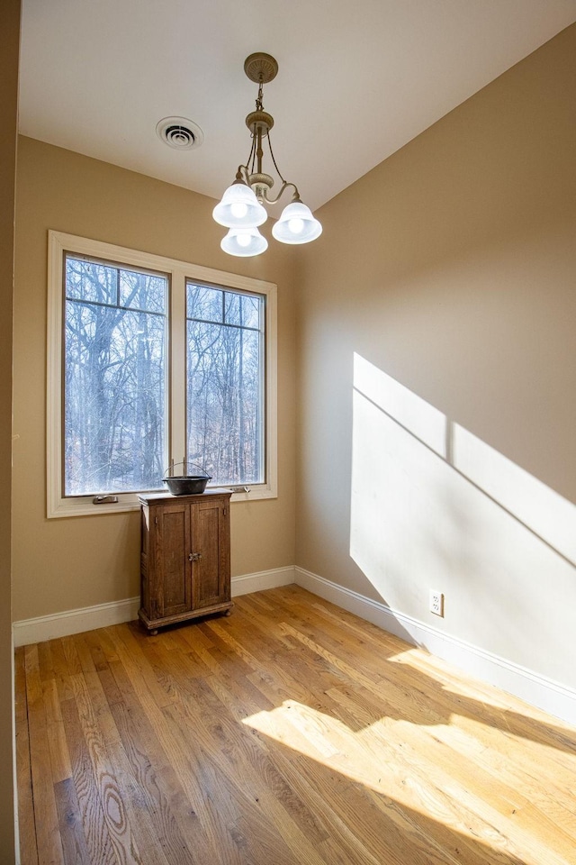 unfurnished dining area with a chandelier and light hardwood / wood-style flooring