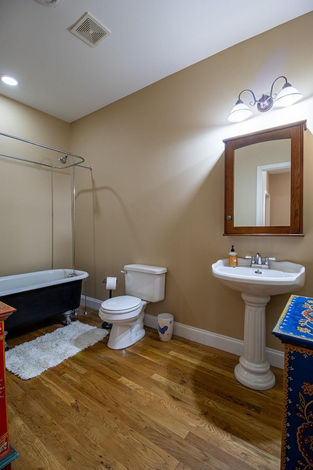 bathroom with toilet, wood-type flooring, and shower / bathtub combination