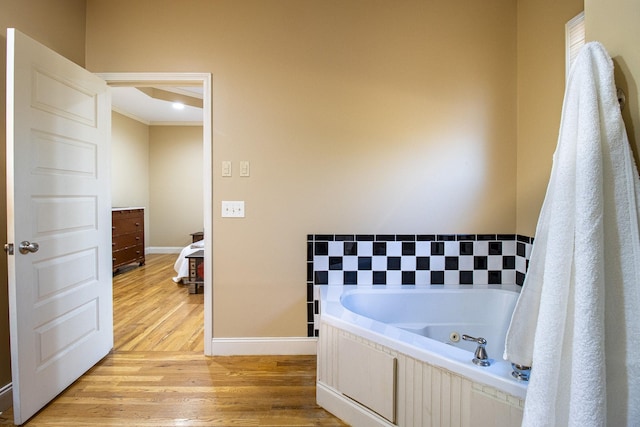 bathroom featuring ornamental molding, a tub to relax in, and wood-type flooring