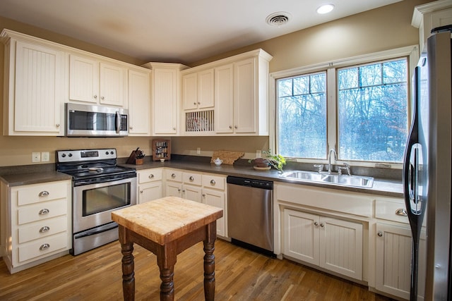 kitchen featuring white cabinets, appliances with stainless steel finishes, hardwood / wood-style flooring, and sink