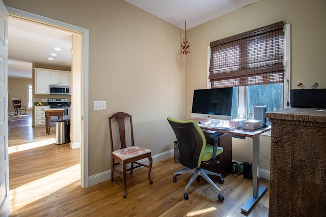 home office with light hardwood / wood-style flooring