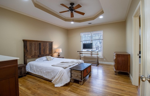 bedroom with ceiling fan, light wood-type flooring, ornamental molding, and a raised ceiling