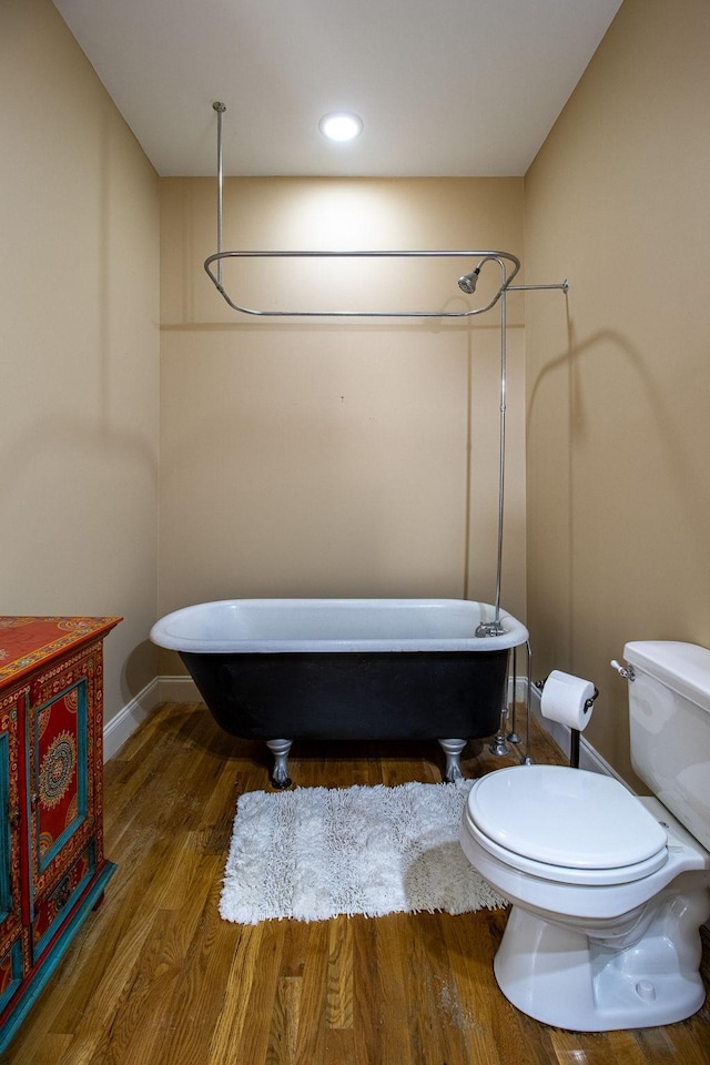 bathroom with a tub, toilet, and hardwood / wood-style flooring