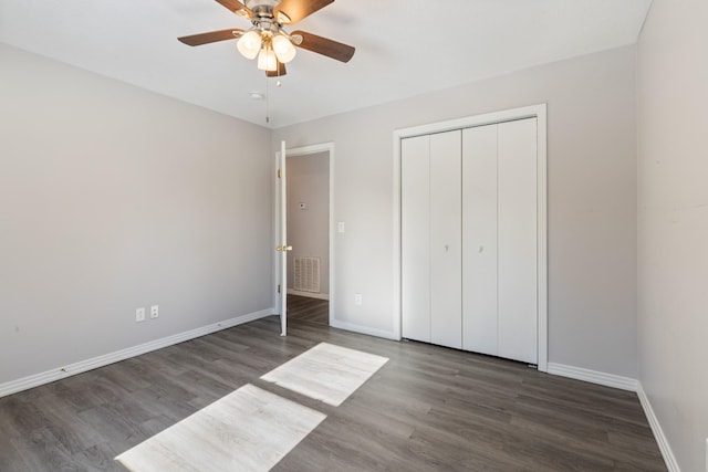 unfurnished bedroom with ceiling fan, dark wood-type flooring, and a closet