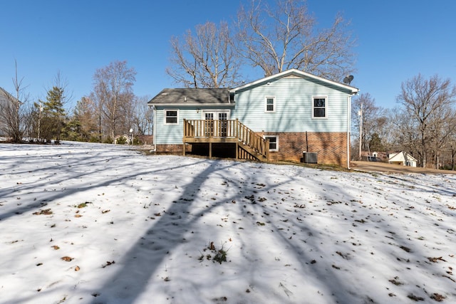 snow covered back of property featuring central air condition unit and a wooden deck