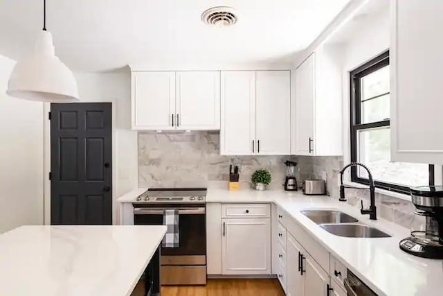 kitchen featuring electric stove, decorative backsplash, white cabinets, decorative light fixtures, and sink