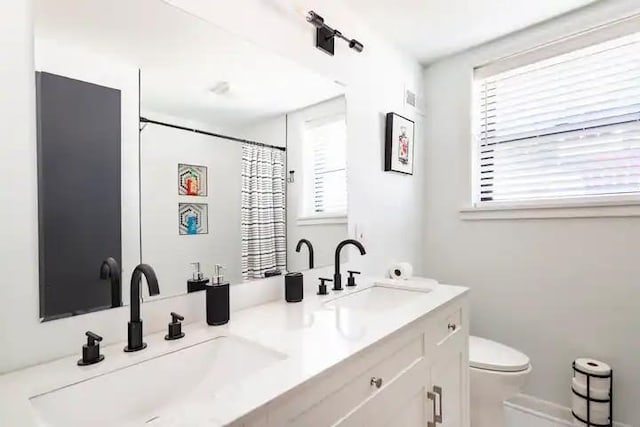 bathroom featuring toilet, plenty of natural light, and vanity