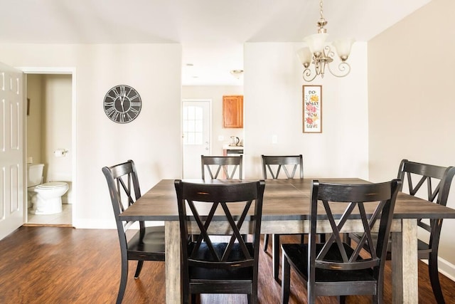 dining area featuring dark wood-type flooring and an inviting chandelier