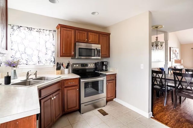 kitchen featuring sink, decorative light fixtures, light tile patterned flooring, a notable chandelier, and appliances with stainless steel finishes