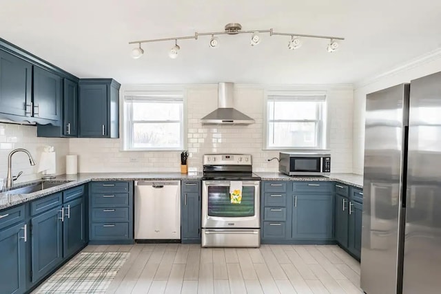 kitchen featuring sink, stainless steel appliances, blue cabinets, and wall chimney exhaust hood