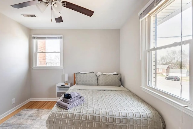 bedroom with multiple windows, ceiling fan, and light hardwood / wood-style floors