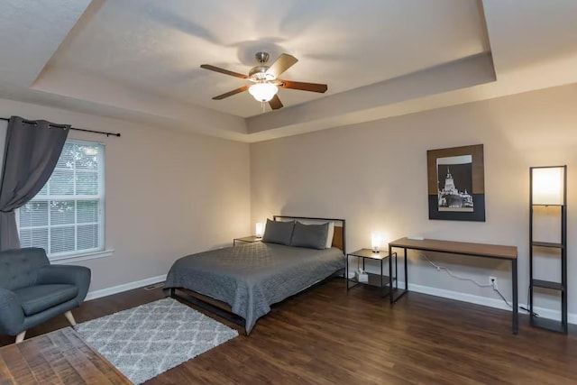 bedroom featuring dark wood-type flooring, ceiling fan, and a tray ceiling