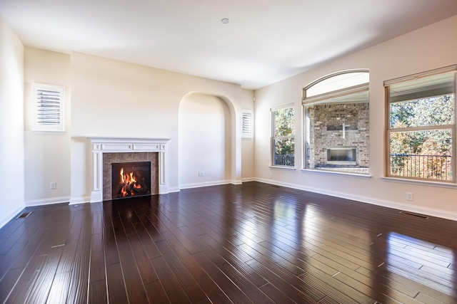 unfurnished living room with a tile fireplace and dark hardwood / wood-style flooring