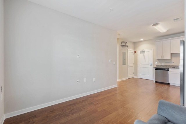 kitchen with white cabinets, stainless steel appliances, light stone countertops, and wood-type flooring