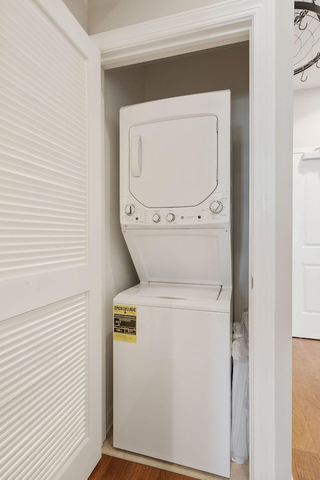 clothes washing area featuring stacked washer and clothes dryer and wood-type flooring