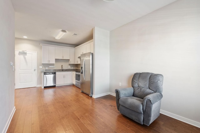 kitchen featuring hardwood / wood-style floors, stainless steel appliances, sink, and white cabinetry