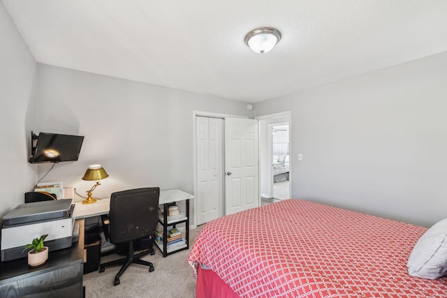 bedroom with a textured ceiling, carpet floors, and a closet