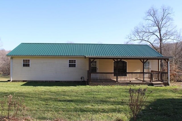 rear view of property with a wooden deck and a lawn