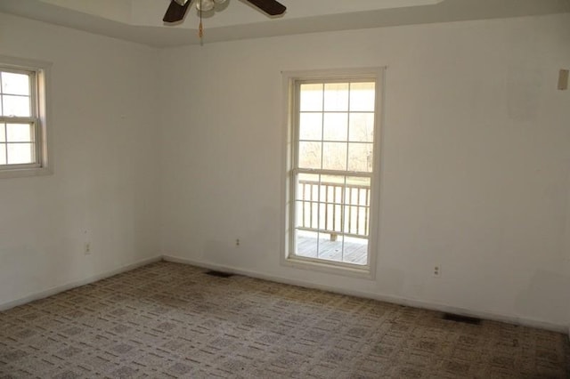 spare room with carpet, ceiling fan, and a tray ceiling