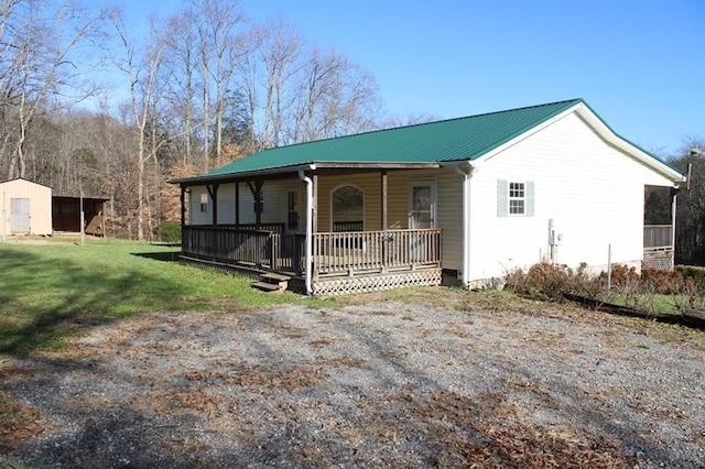 view of front facade featuring covered porch, a storage shed, and a front lawn