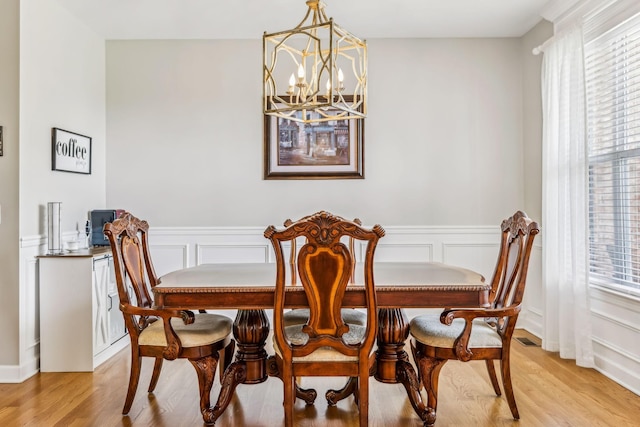 dining area with light wood-type flooring and a chandelier