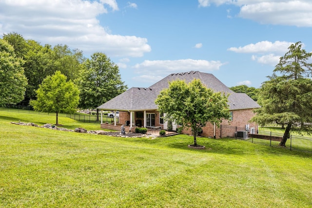 rear view of property with a yard, central air condition unit, and a patio