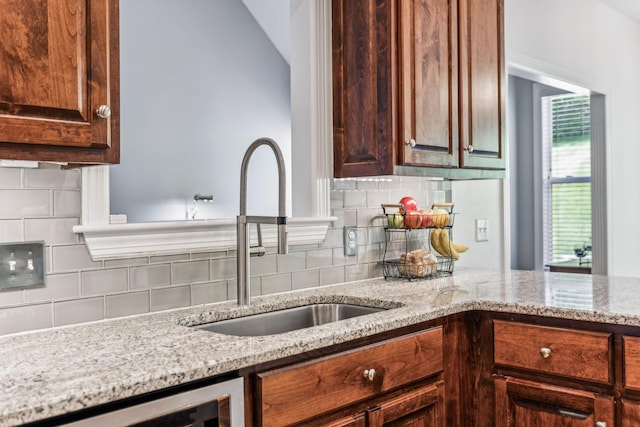 kitchen featuring light stone counters, tasteful backsplash, lofted ceiling, wine cooler, and sink