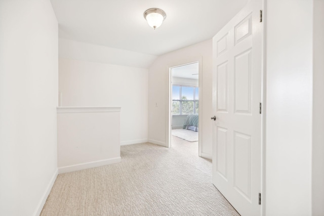 corridor with lofted ceiling and light colored carpet