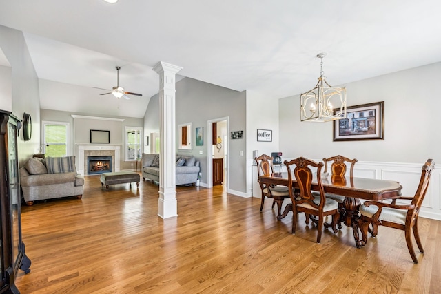 dining area with light hardwood / wood-style flooring, a tile fireplace, lofted ceiling, and ceiling fan with notable chandelier