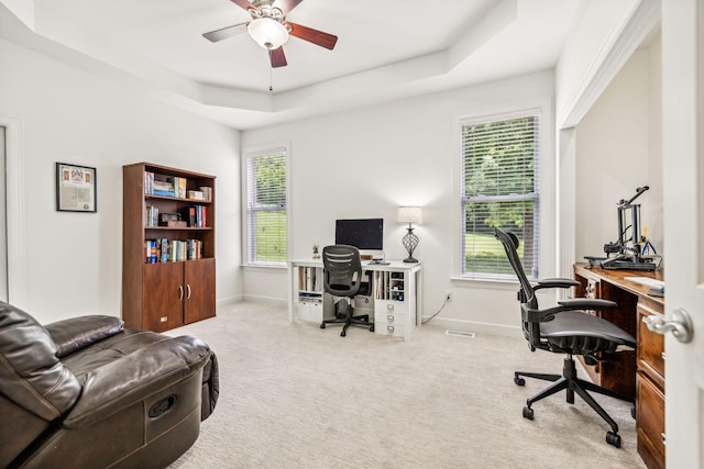 office area featuring ceiling fan, light carpet, plenty of natural light, and a tray ceiling