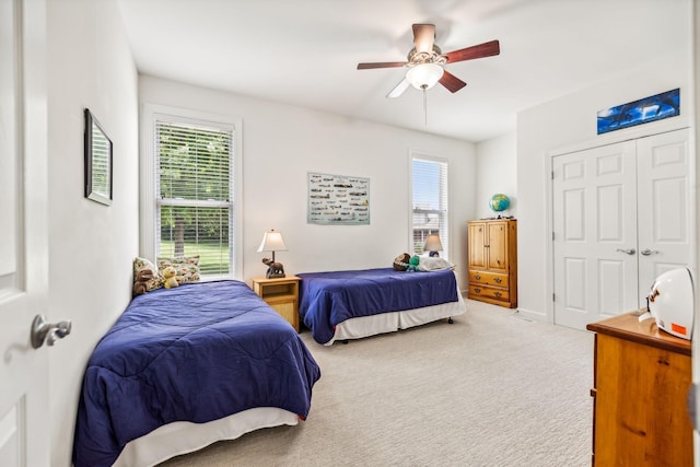 bedroom with carpet floors, ceiling fan, a closet, and multiple windows