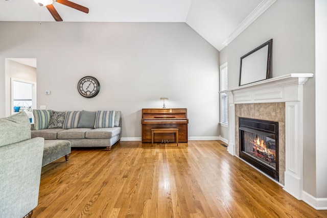 living room featuring a tile fireplace, ceiling fan, light hardwood / wood-style flooring, and a healthy amount of sunlight