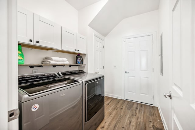 laundry room featuring cabinets, light wood-type flooring, and washing machine and clothes dryer