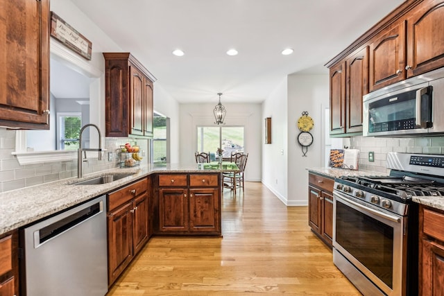 kitchen featuring stainless steel appliances, sink, a healthy amount of sunlight, and kitchen peninsula