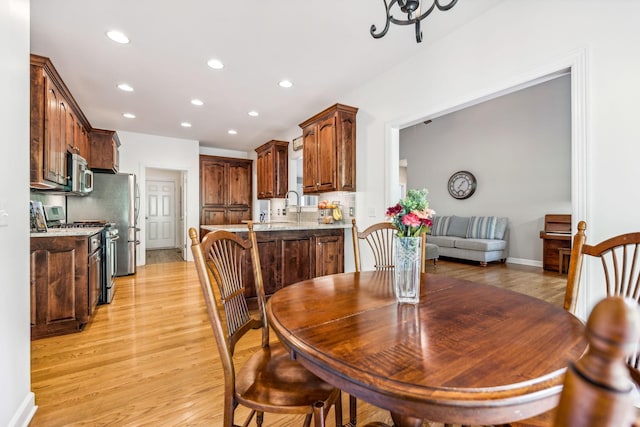 dining space with sink, an inviting chandelier, and light hardwood / wood-style flooring