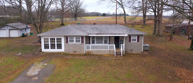 view of front of property featuring a porch, central air condition unit, a garage, and an outbuilding