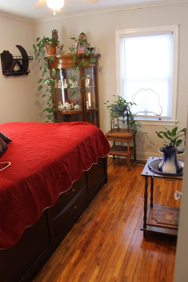 bedroom featuring hardwood / wood-style floors, ornamental molding, ceiling fan, and multiple windows