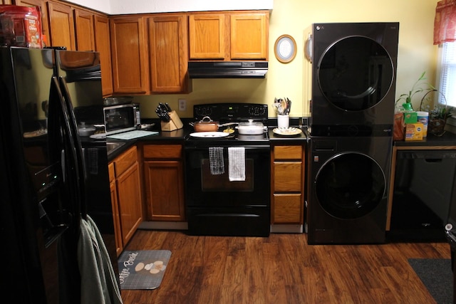 kitchen featuring black appliances, dark wood-type flooring, and stacked washer / drying machine