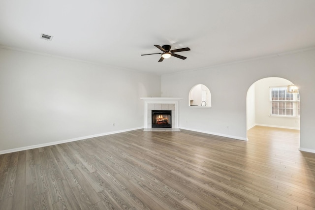 unfurnished living room featuring hardwood / wood-style flooring, ceiling fan, crown molding, and a fireplace