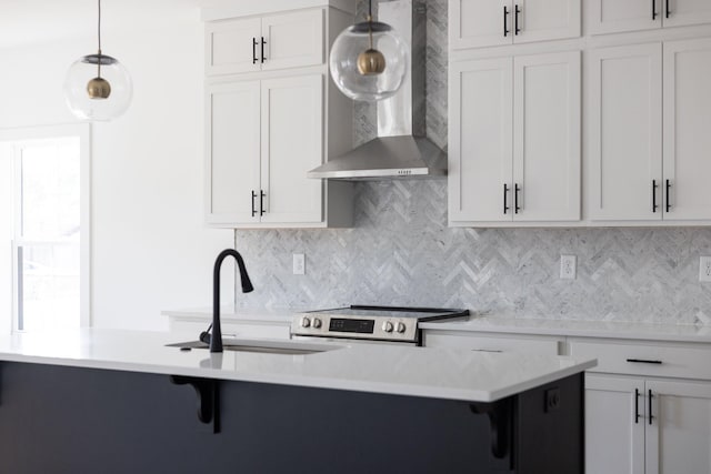 kitchen featuring wall chimney exhaust hood, hanging light fixtures, tasteful backsplash, white cabinets, and sink