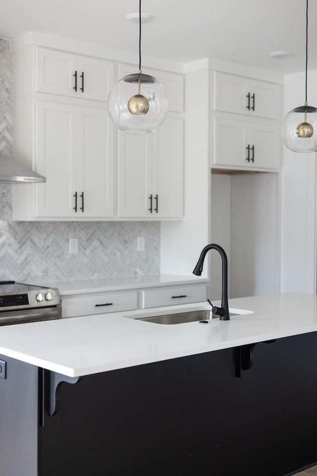 kitchen featuring sink, white cabinetry, stainless steel electric range, wall chimney range hood, and pendant lighting