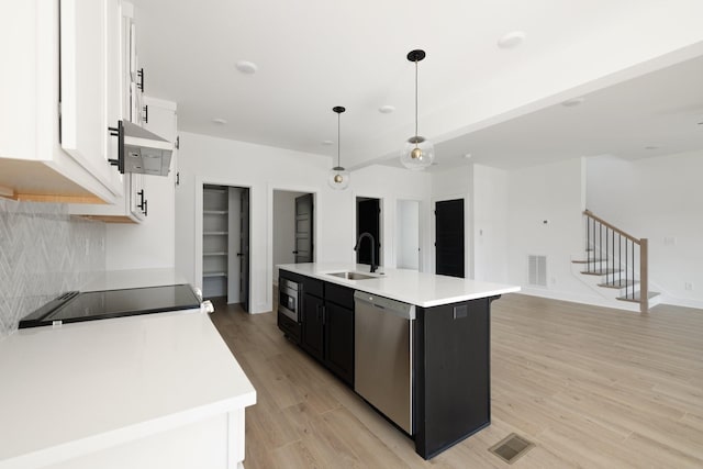 kitchen featuring decorative light fixtures, a kitchen island with sink, white cabinetry, appliances with stainless steel finishes, and sink