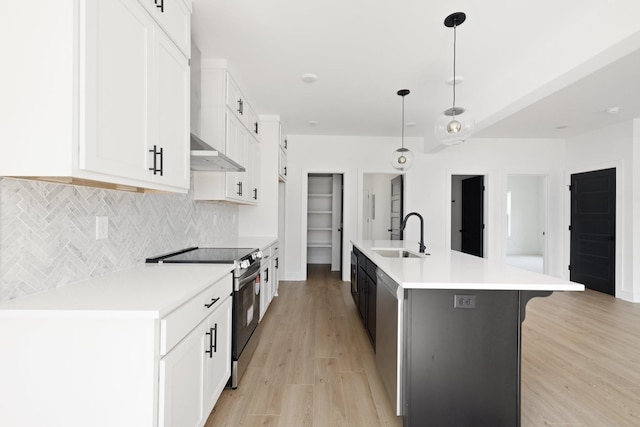 kitchen featuring pendant lighting, a center island with sink, white cabinets, stainless steel range with electric stovetop, and sink