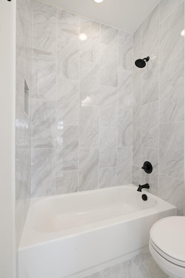 bathroom with toilet and tiled shower / bath