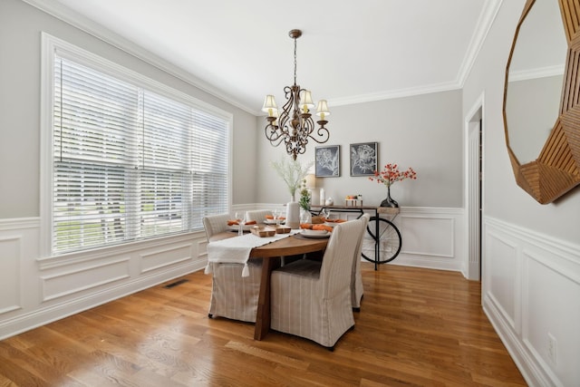 dining room featuring light hardwood / wood-style floors, ornamental molding, and a chandelier