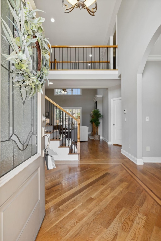 foyer entrance with a notable chandelier, crown molding, a towering ceiling, and hardwood / wood-style flooring