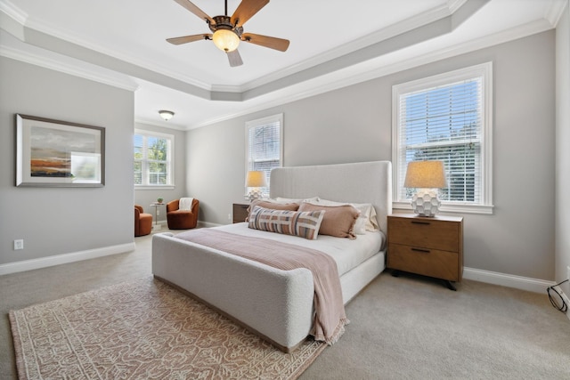 bedroom with ceiling fan, light colored carpet, ornamental molding, and a tray ceiling