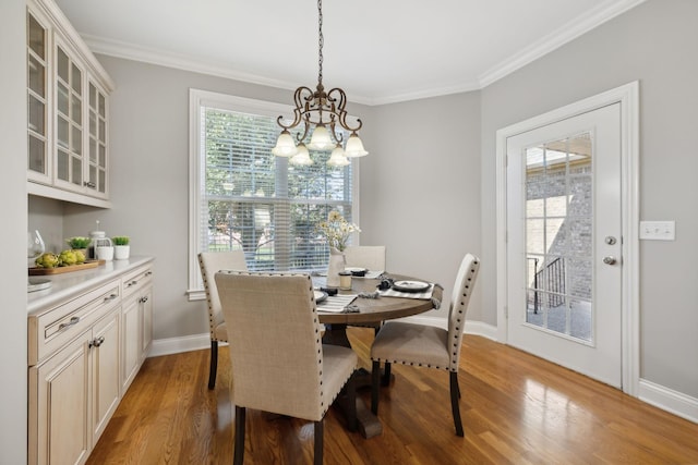 dining space featuring a chandelier, ornamental molding, and light hardwood / wood-style flooring