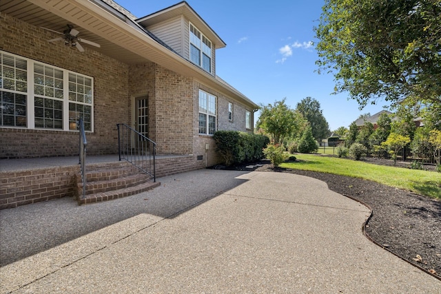 view of side of home featuring ceiling fan, a lawn, and a patio area