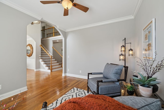 sitting room with ceiling fan, ornamental molding, and wood-type flooring